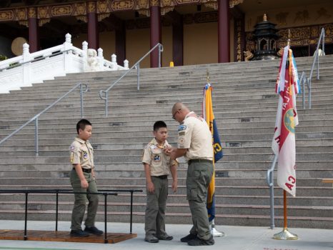 幼童軍 Adrian Lin(中)逐一跨越由17片木板組成的橋，象徵童軍成長過程中的不同階段。