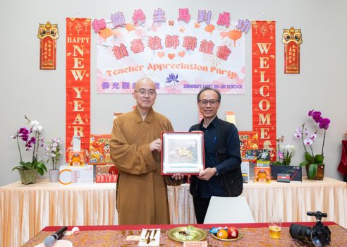 慧東法師(左)頒發精美摸彩品予幸運中獎的西來寺文宣組張志誠。