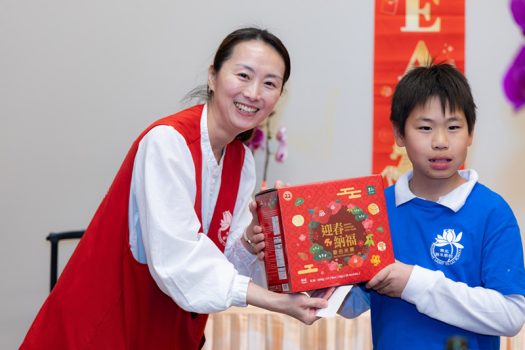 10 歲的小小茶師Adrian Lin(右)頒發精美摸彩品予幸運中獎的教師。
