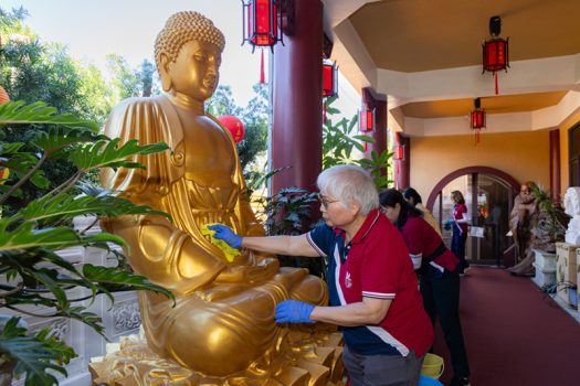 義工們以恭敬心擦拭長廊上的佛像。