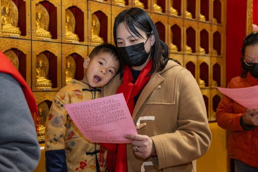 小朋友乖巧地依偎在媽咪懷裡參與法會。