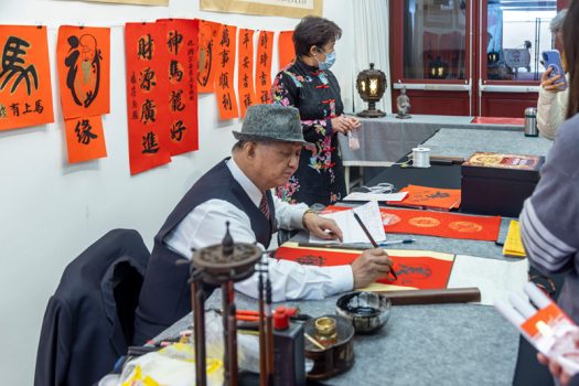 潘慶忠案前揮毫不輟，馬不停蹄應民眾請求書寫春聯吉語。