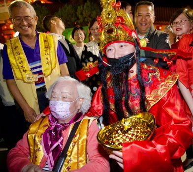 象徵吉祥富貴的財神爺手捧金元寶穿梭人群，與信眾歡喜合影。