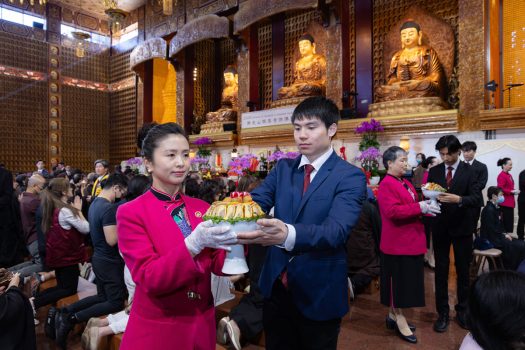 佛光知賓組獻供人員面帶微笑將供菜交由侍席人員。