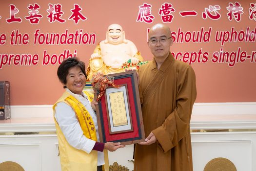 晚宴穿插摸彩，慧東法師(右)與喜獲最大獎——星雲大師墨寶「和諧共生 馬到成功」匾額的佛光西來學校義工郭麗珍(左)合影。